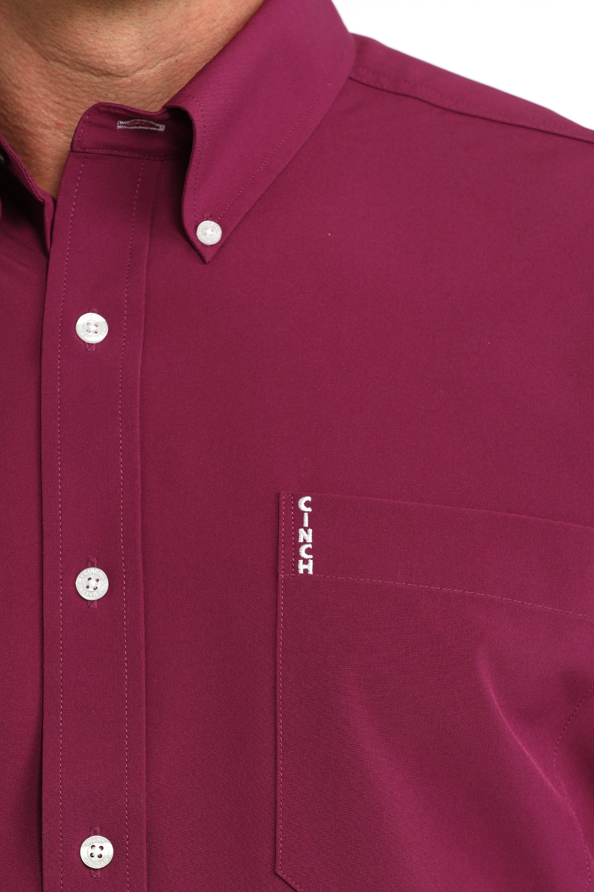 Close-up of a maroon Cinch shirt with a visible brand logo on a white background