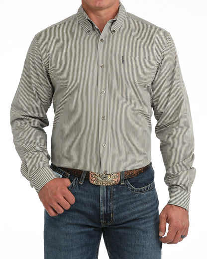 A man wearing a long-sleeve button-down Cinch shirt with thin vertical pinstripes in beige and gray, paired with blue jeans and a western belt.