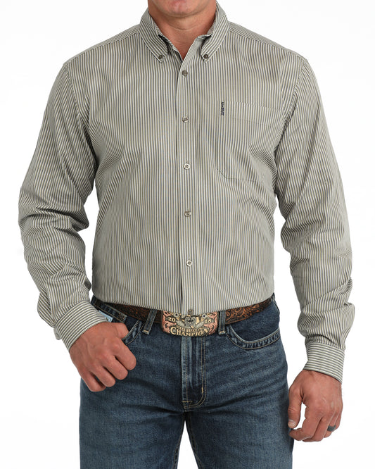 A man wearing a long-sleeve button-down Cinch shirt with thin vertical pinstripes in beige and gray, paired with blue jeans and a western belt.