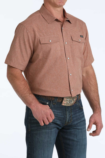Man wearing a brown short-sleeve 'Cinch' shirt and blue jeans on a white background