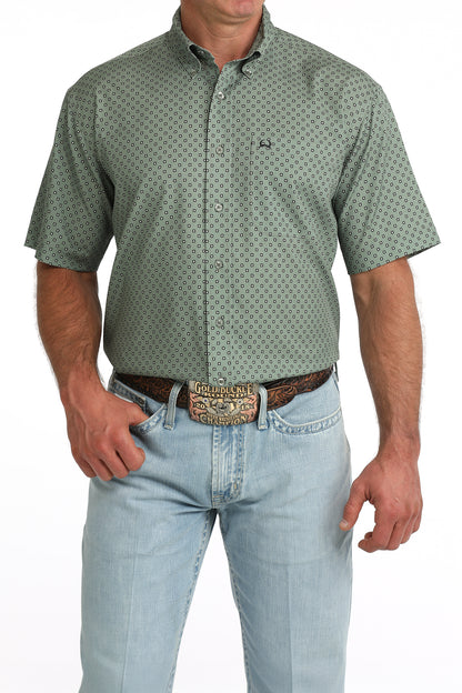 man wearing an olive green Cinch shirt and blue jeans on a white background