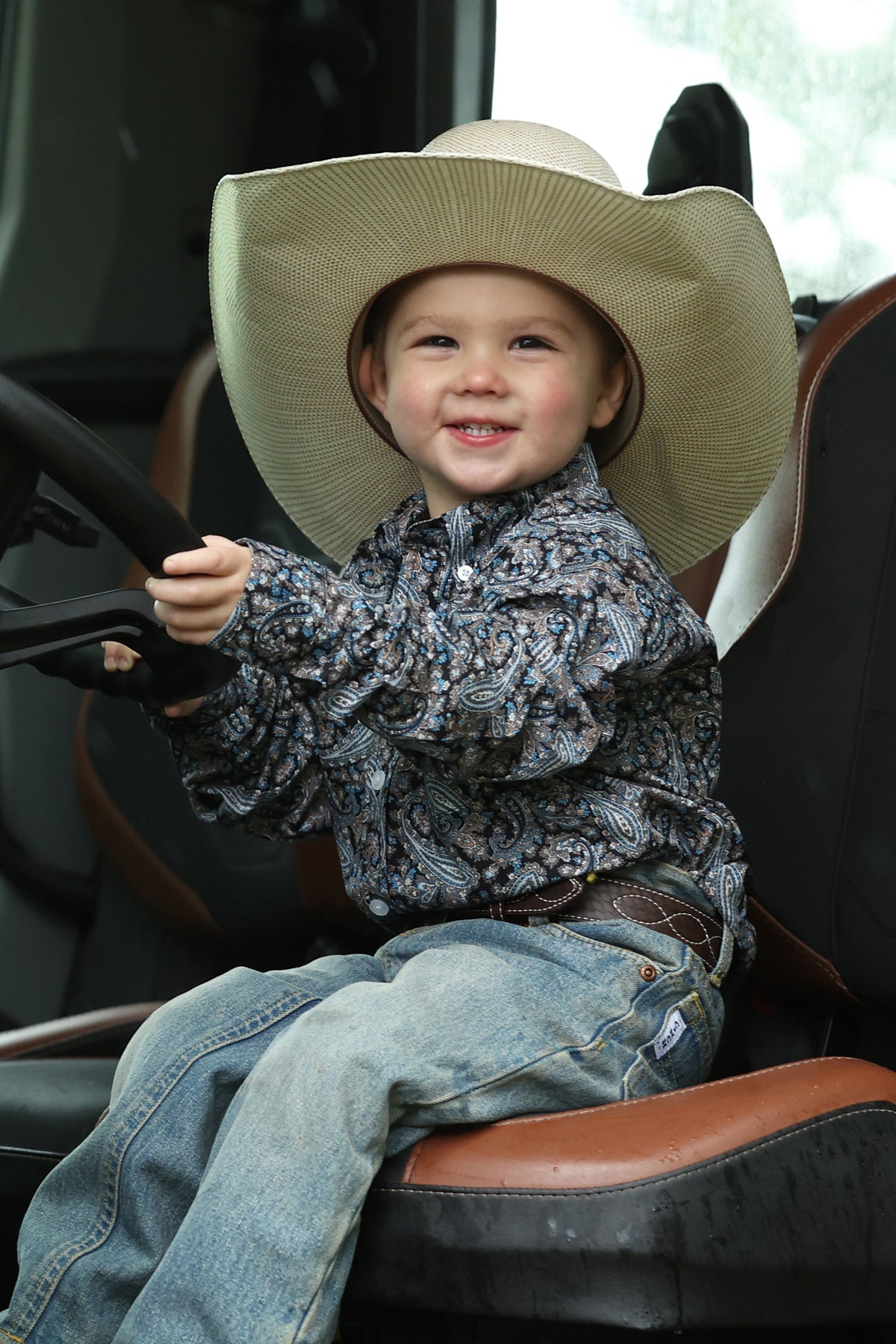 Boy wearing Blue Cinch shirt and blues jeans and a hat