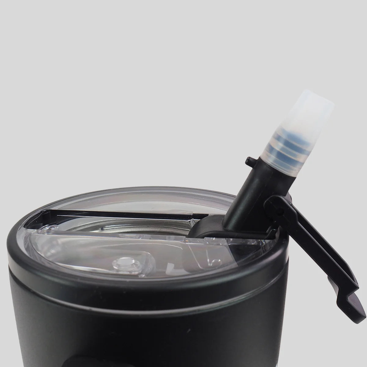 Close-up of a black insulated tumbler from Kerusso with a clear lid and a black straw-style drink spout with a translucent white cap, shown on a light gray background.