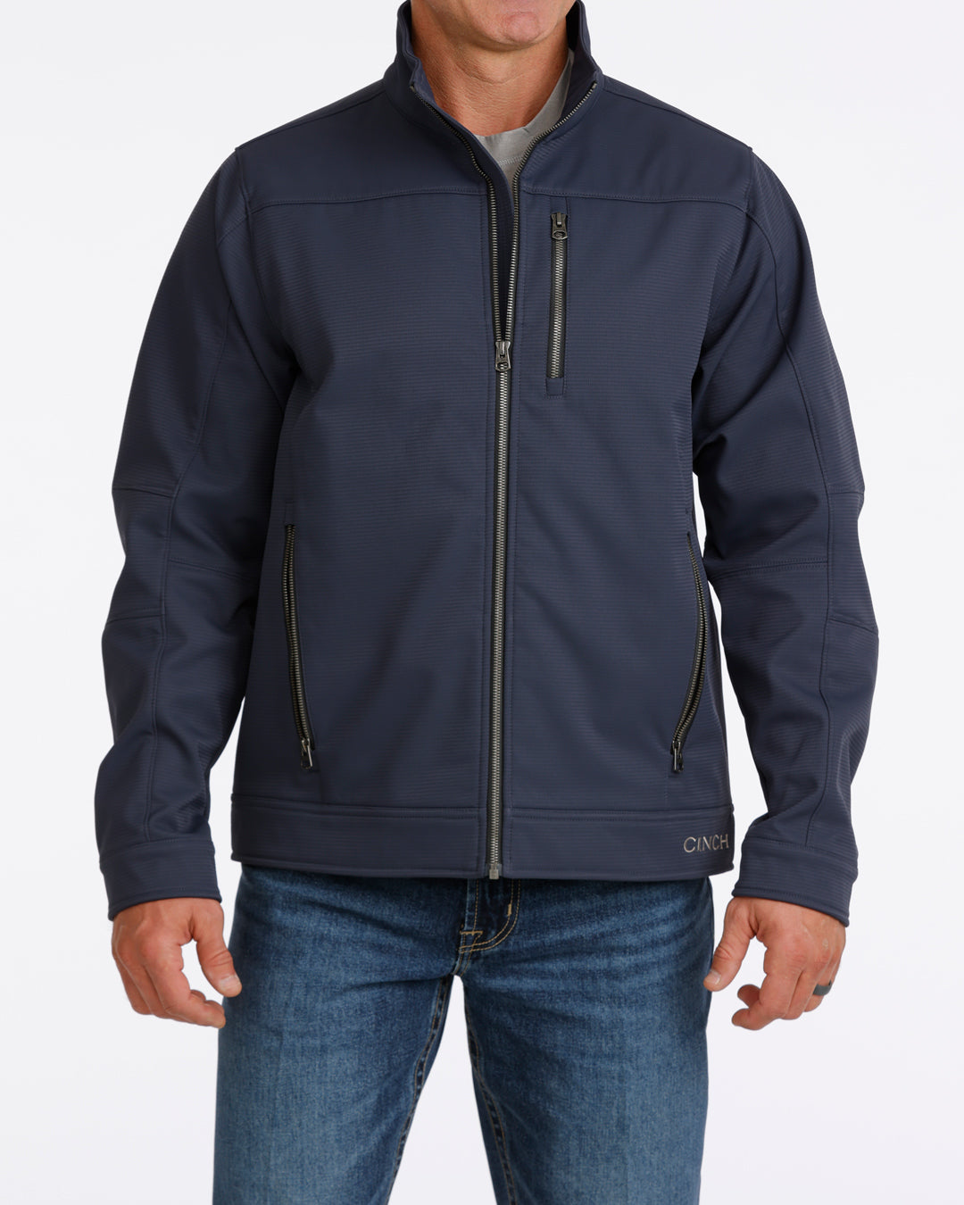 Man wearing a navy Cinch jacket and blue jeans on a white background