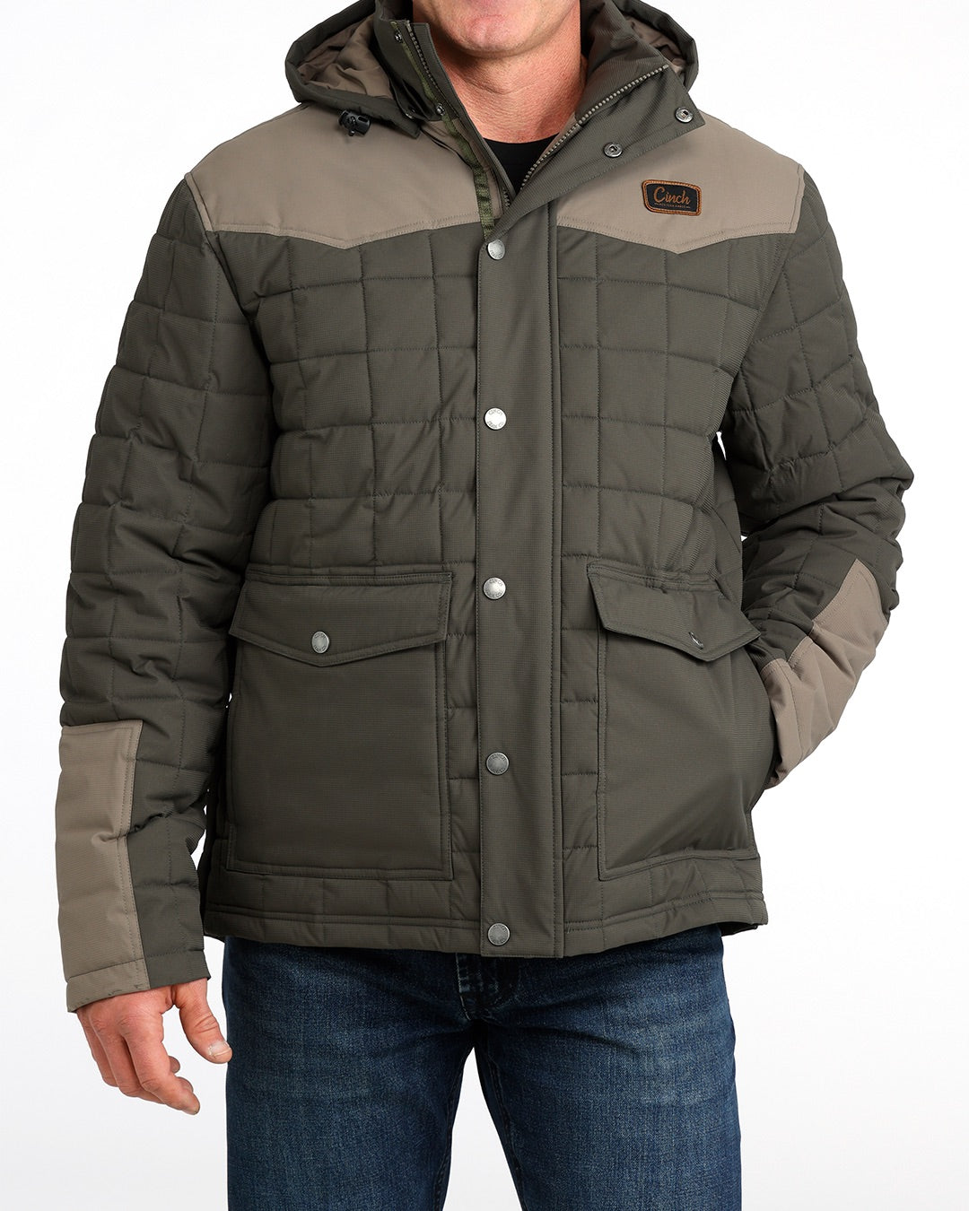Man wearing a thick barn coat by Cinch and blue jeans on a grey background