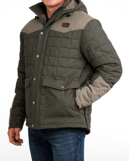 Man wearing a thick barn coat by Cinch and blue jeans on a grey background