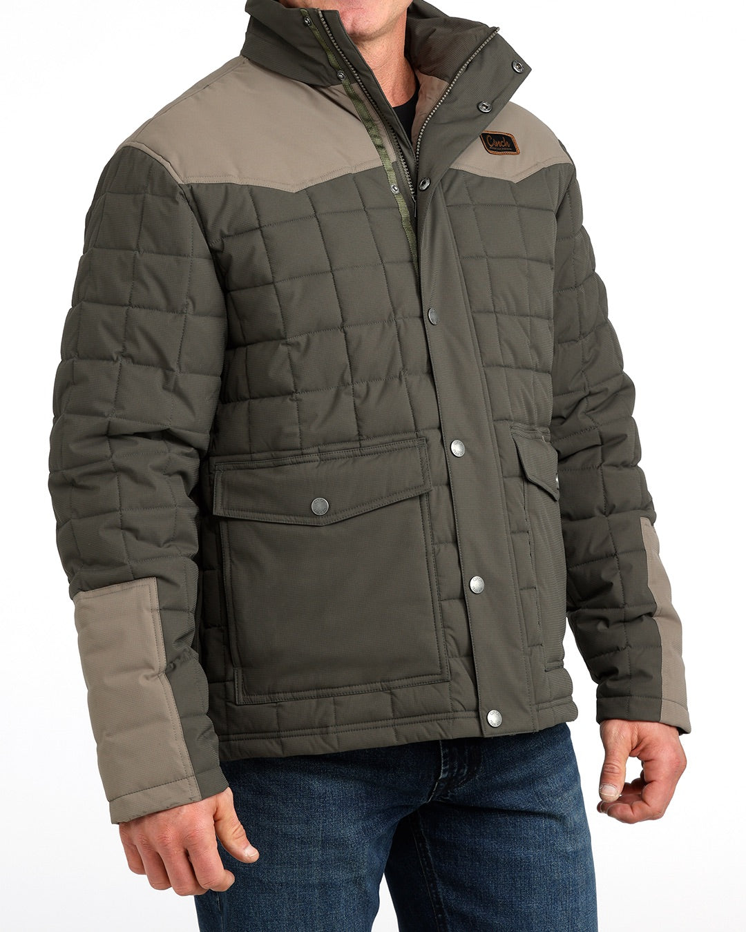 Man wearing a thick barn coat by Cinch and blue jeans on a grey background