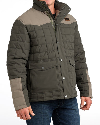 Man wearing a thick barn coat by Cinch and blue jeans on a grey background