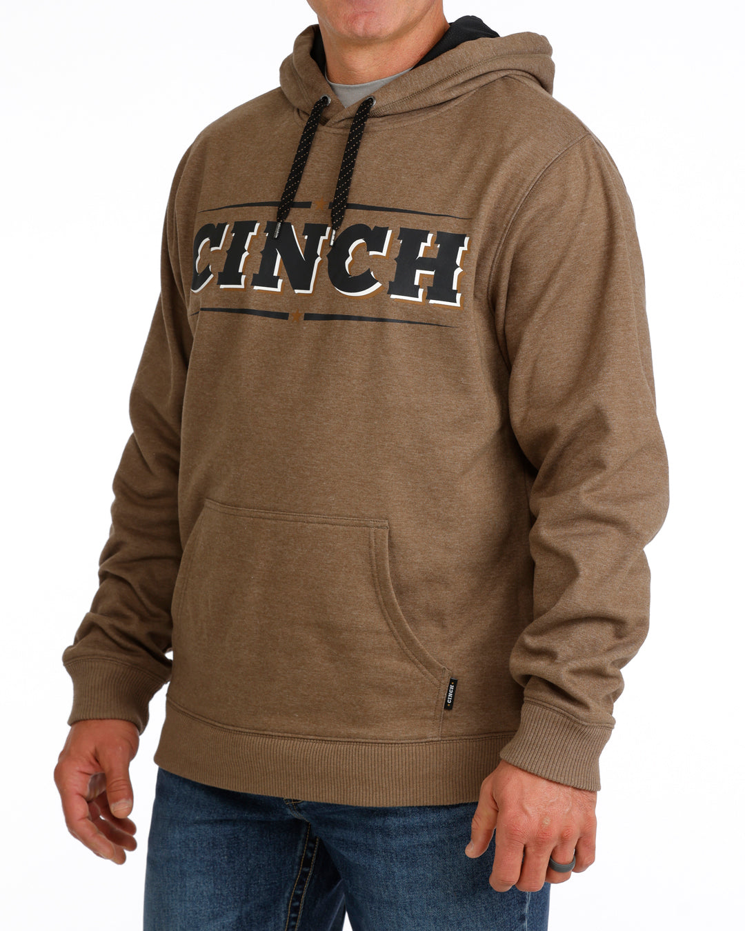 A man wearing a brown heathered pullover hoodie with 'CINCH' printed across the chest in black and white varsity lettering, paired with blue jeans against a white studio background.