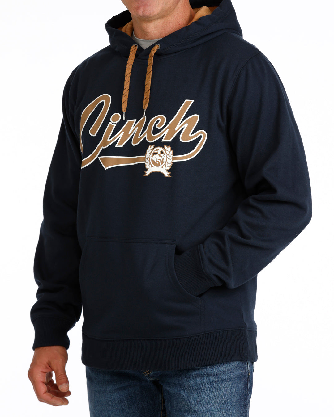 A man wearing a navy blue hoodie with a large gold and white 'Cinch' script logo across the chest, paired with blue jeans against a plain white background.