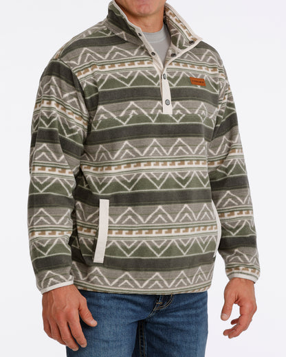 Man wearing an olive Cinch fleece pullover and blue jeans on a white background