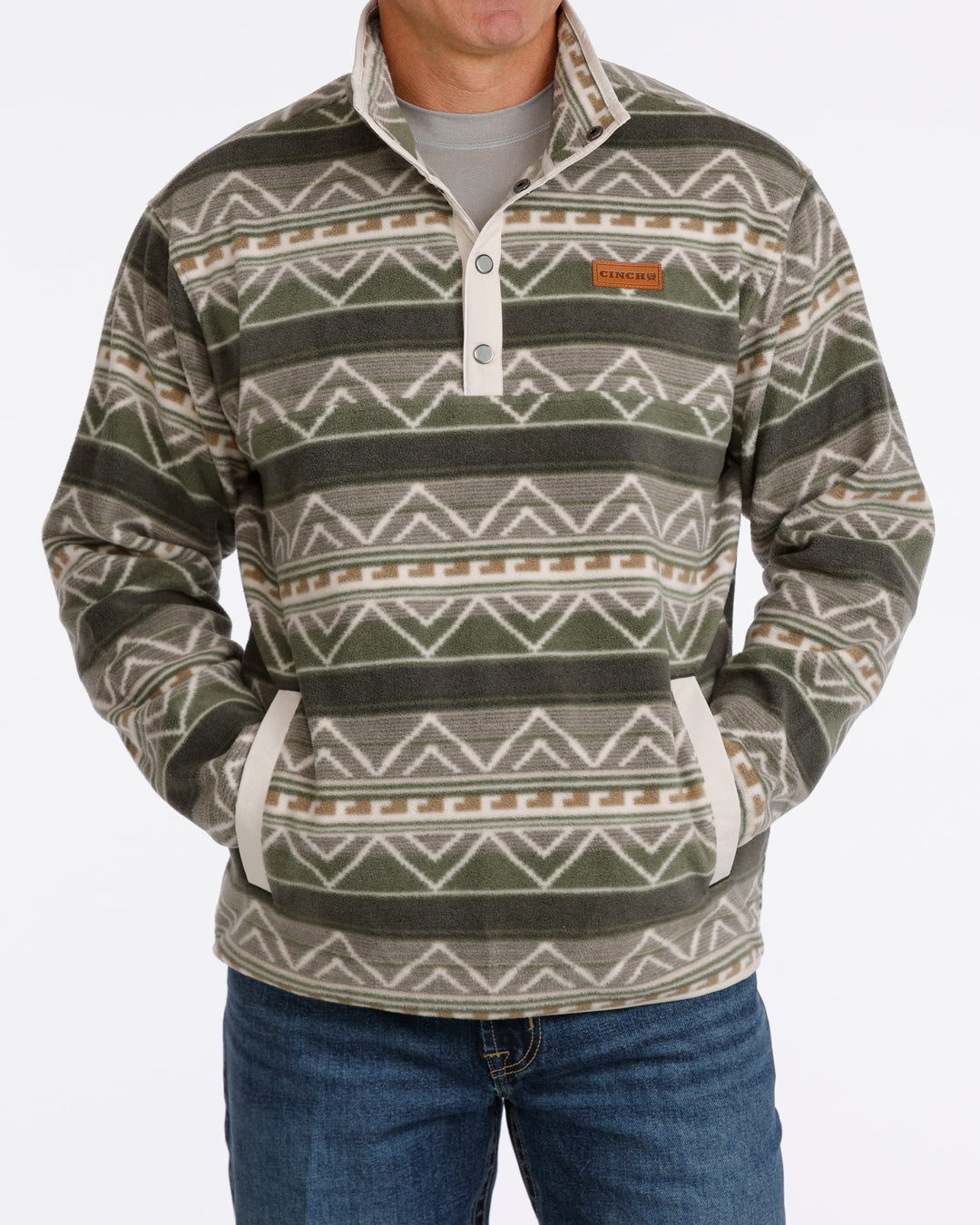 Man wearing an olive Cinch fleece pullover and blue jeans on a white background