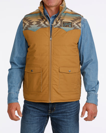 man wearing a tan Cinch vest with bue aztec design, denim shirt and blue jeans on a white background