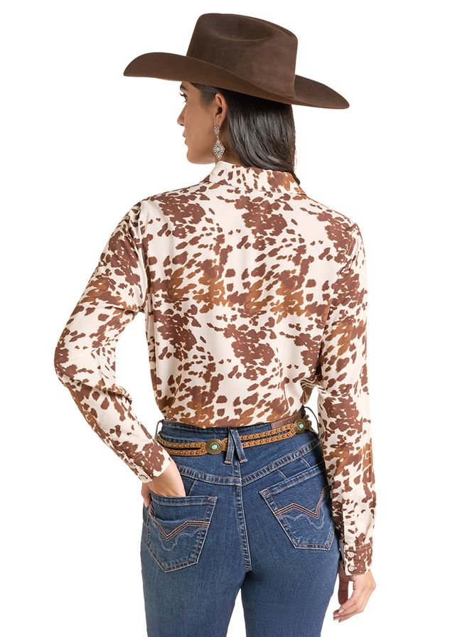woman wearing a cowhide print shirt from Panhandle Slim and blue jeans and a brown cowboy hat on a white background