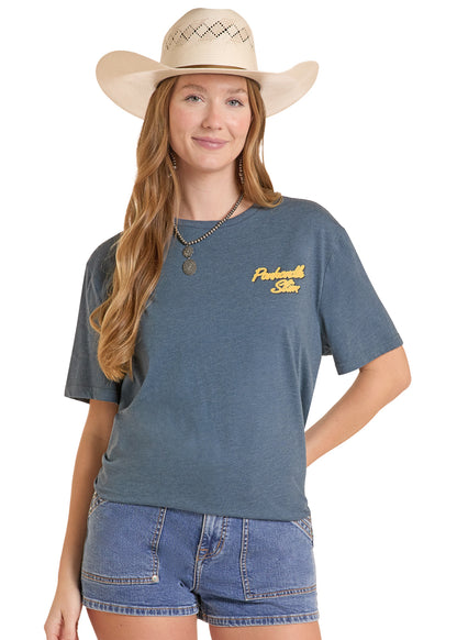 woman wearing a Panhandle Slim tshirt, jean shorts and cowboy hat on a white background