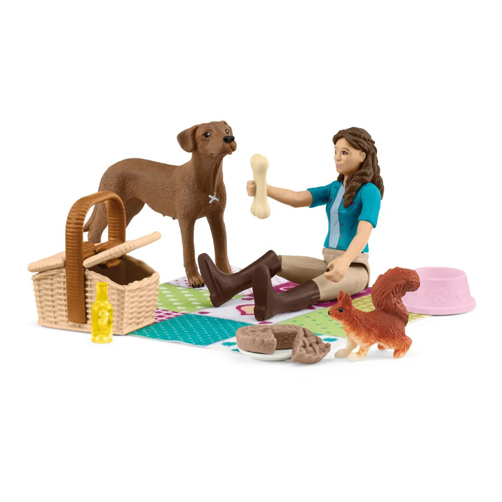 Schleich playset with a woman, dog, and squirrel on a picnic blanket.