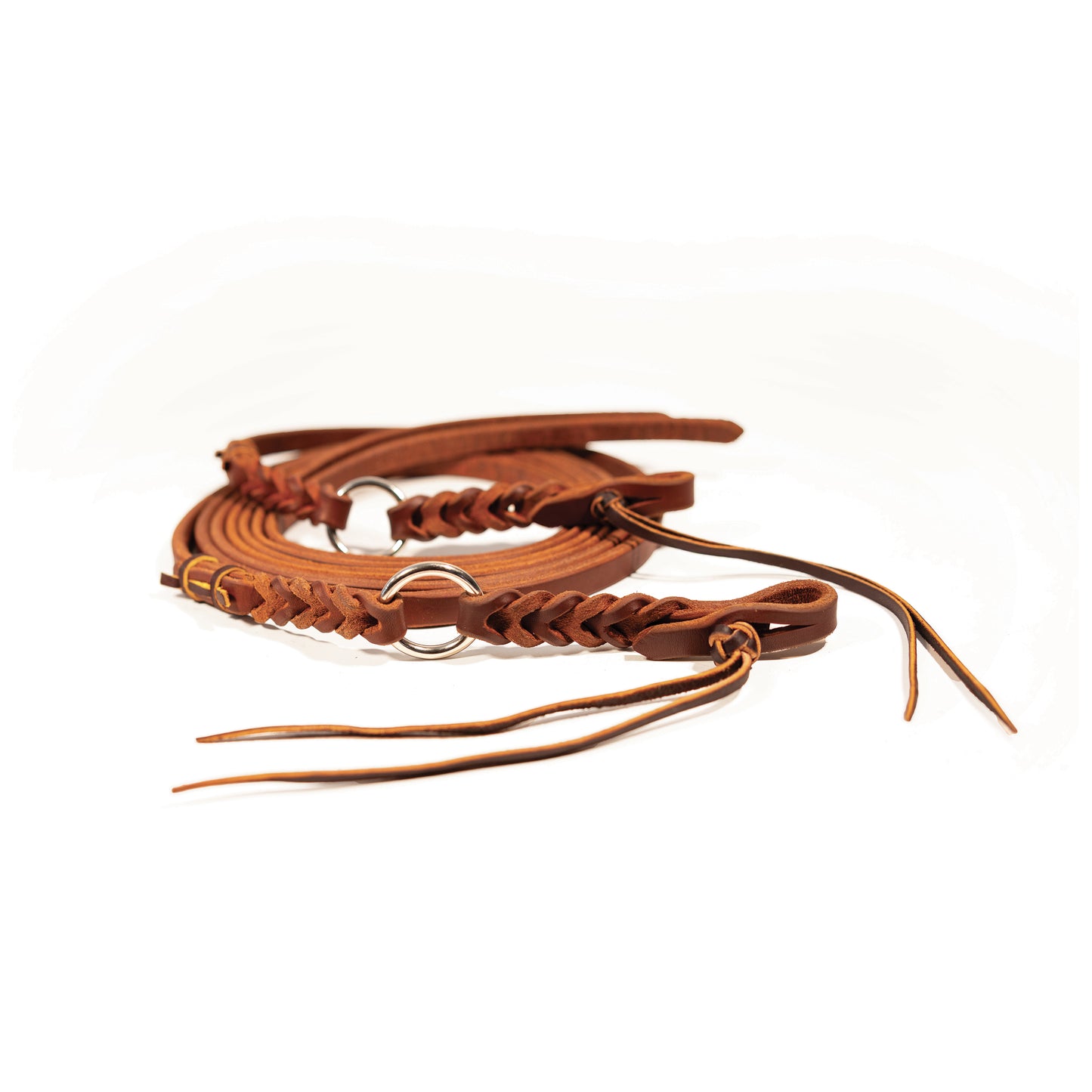a pair of harness leather reins with a silver ring and braid detail coiled up on a white background
