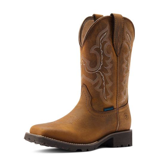 a brown cowboy boot with a waterproof tag and an ariat logo on a white background. The boot has a thicker black outsole.