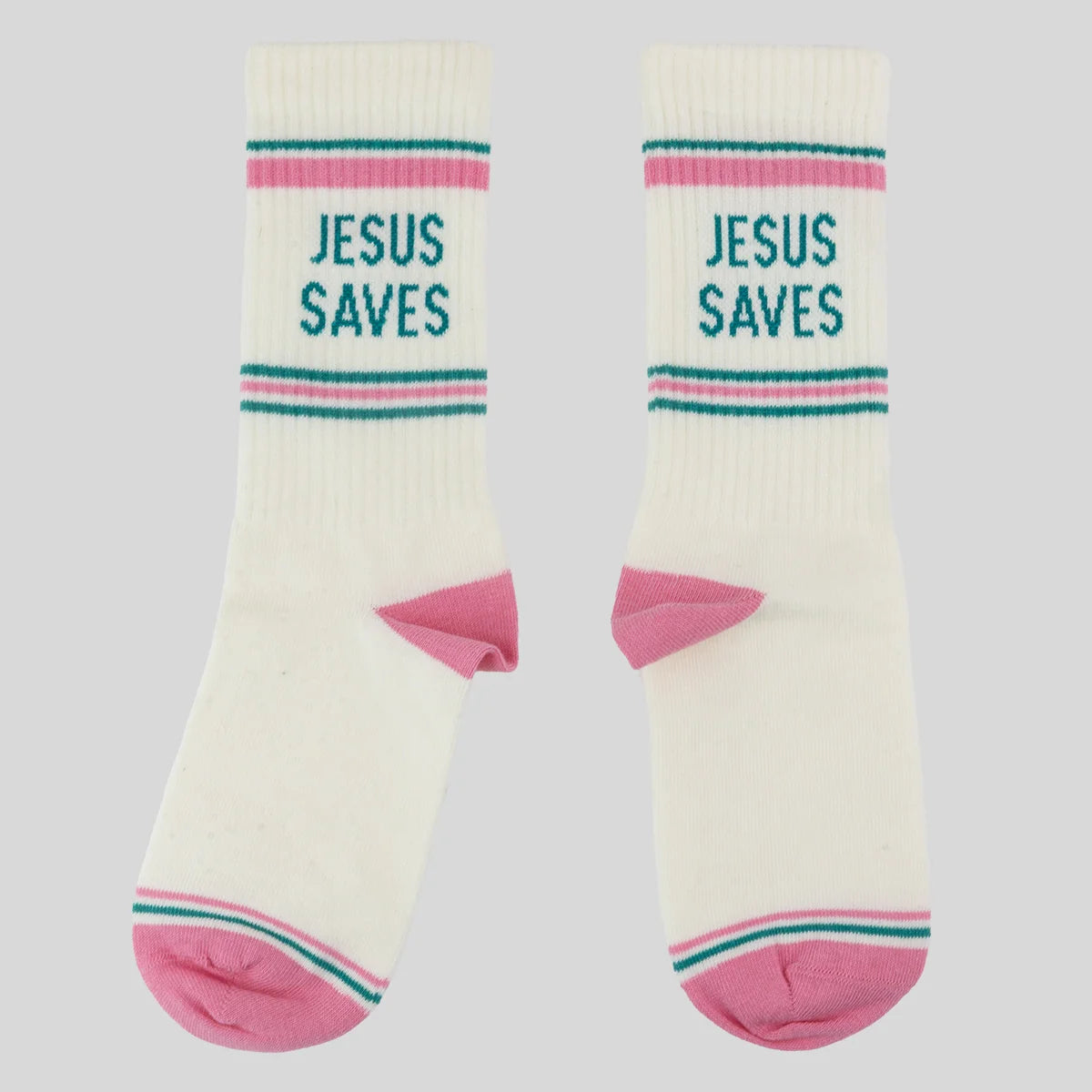 A pair of off-white crew socks from Kerusso with pink heels and toes, featuring teal and pink stripes near the cuff with the text 'JESUS SAVES' printed in teal. Photographed on a solid light gray background.