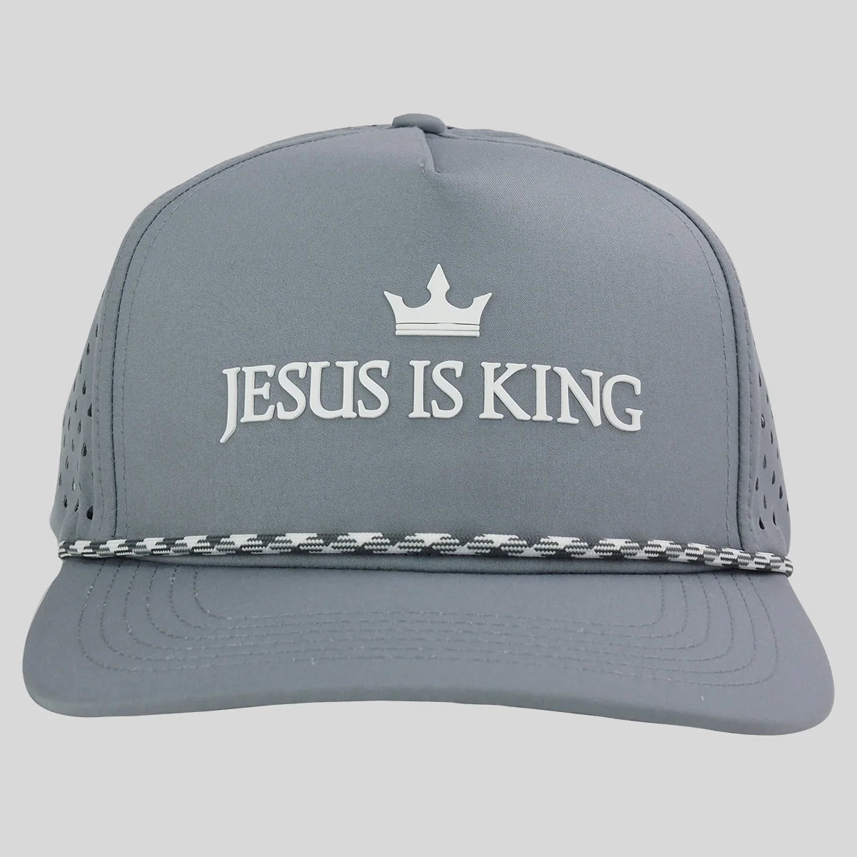 A gray trucker-style cap from Kerusso with white embroidered text reading 'JESUS IS KING' under a small white crown, plus a black-and-white patterned rope detail across the brim, shown on a light gray background.