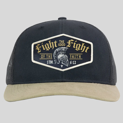 A black trucker hat from Kerusso with a beige curved brim and a large front patch that reads 'Fight the Good Fight of the Faith 1 Tim 6:12' with a Spartan helmet graphic.