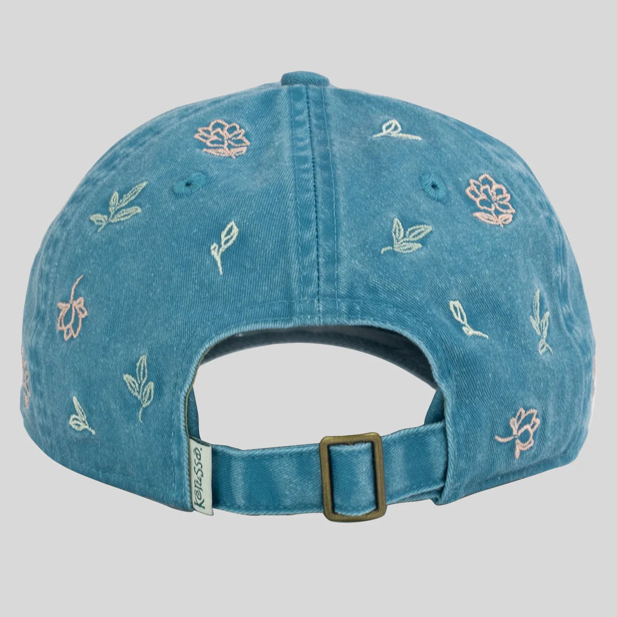 A blue denim baseball cap from Kerusso shown from the back, featuring embroidered floral and leaf motifs in light pink and white, with an adjustable strap and brass buckle.