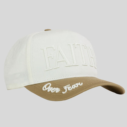 A baseball cap from Kerusso with an off-white crown featuring embossed 'FAITH' lettering and a tan visor with 'Over Fear' script embroidery, shown on a solid gray background.