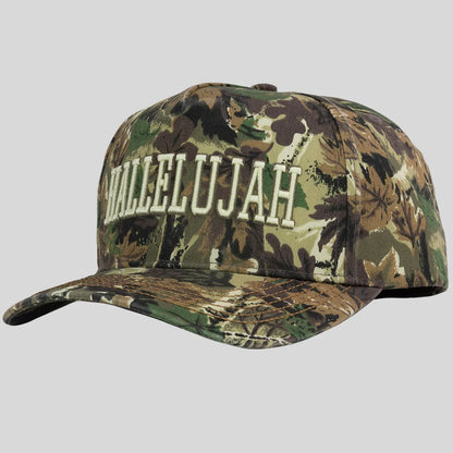 A baseball cap from Kerusso with a woodland camouflage pattern and the word 'HALLELUJAH' embroidered in white arched letters across the front, shown on a solid gray background.