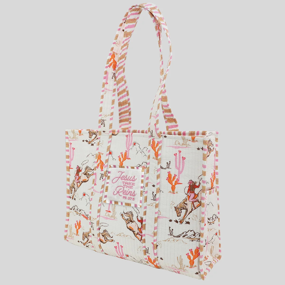 A tote bag from Kerusso with a western-themed print featuring cacti, cowboy boots, and a central patch . The bag has a cream background with pink, orange, and brown illustrations, and matching patterned shoulder straps, set against a solid light gray background.