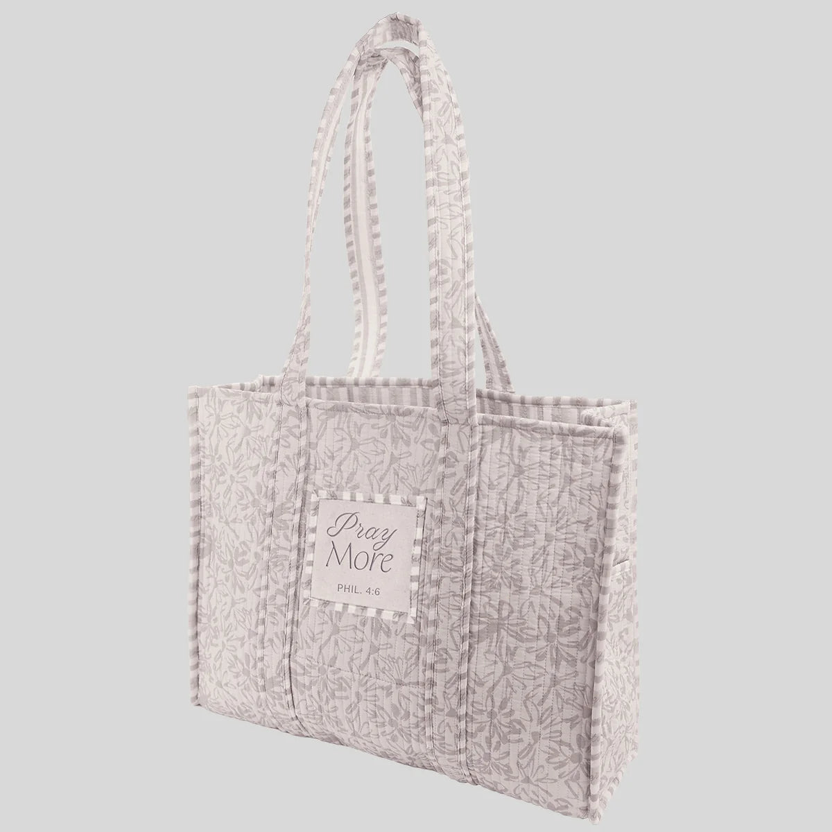 A light gray and white patterned tote bag from Kerusso with quilted side panels and a central label that reads 'Pray More Phil 4:6', shown against a solid gray background.