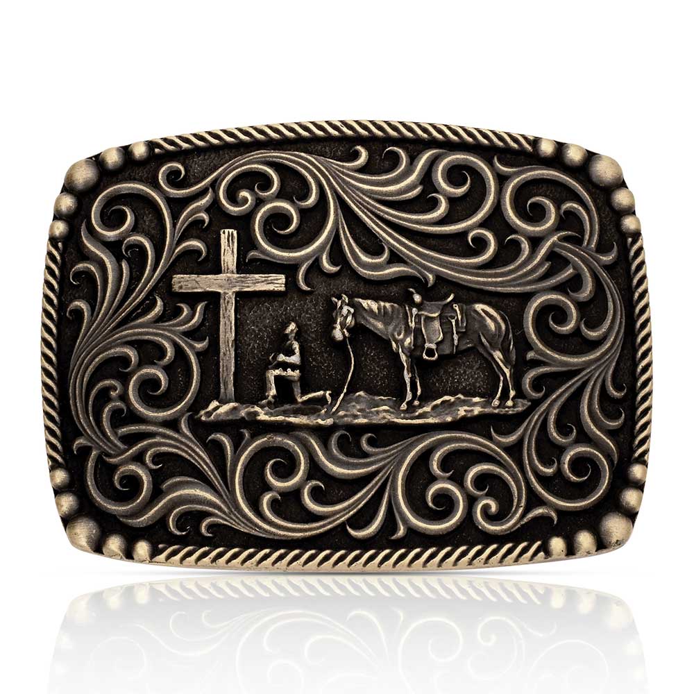 Decorative Montana Silversmiths belt buckle with cross, horse, and rider design on a white background