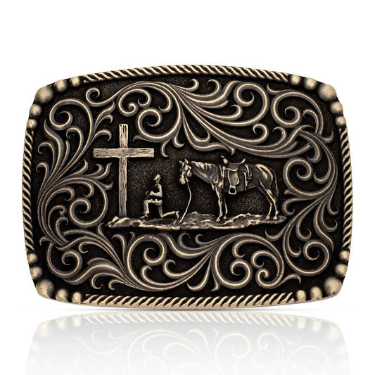 Decorative Montana Silversmiths belt buckle with cross, horse, and rider design on a white background