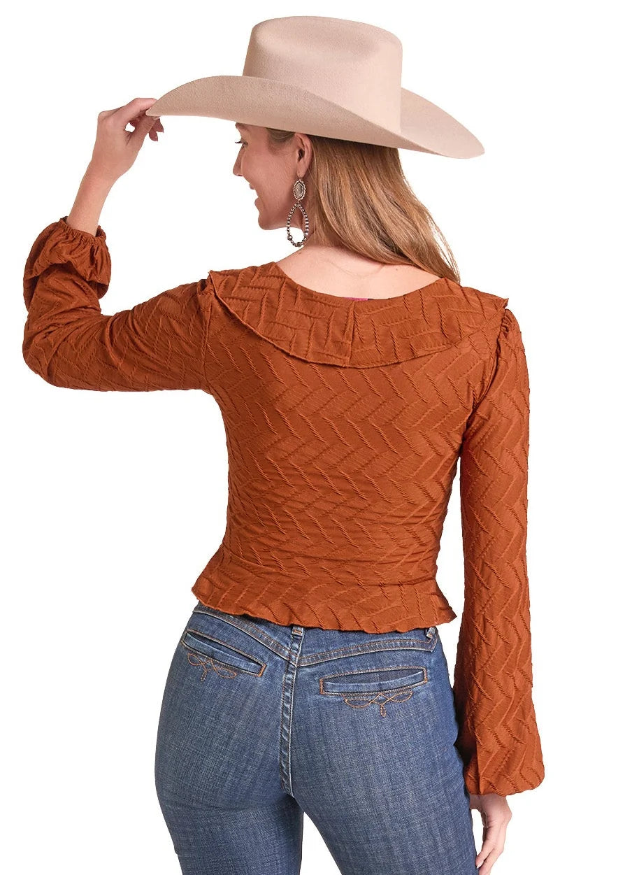 Woman wearing a rust colored shirt fom Rock&Roll Denim, blue jeans and a cream colored cowboy hat on a white background