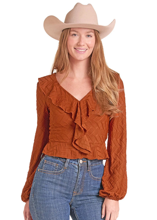 Woman wearing a rust colored shirt fom Rock&Roll Denim, blue jeans and a cream colored cowboy hat on a white background