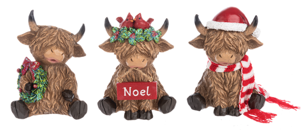 Three Highland cow Christmas figurines from Ganz on a white background. The left cow holds a green wreath with a red bow.