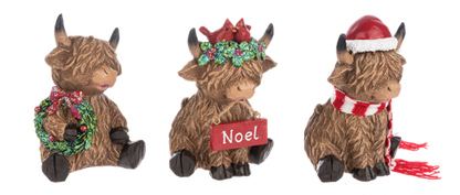Three Highland cow Christmas figurines from Ganz on a white background. The left cow holds a green wreath with a red bow.