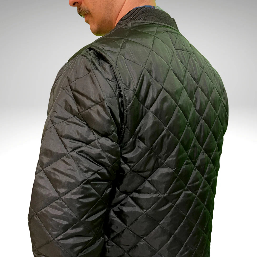 Person wearing a black quilted jacket on a plain background