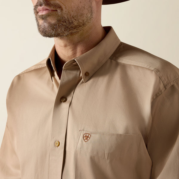 Man wearing a beige Ariat shirt with a brand logo on a neutral background