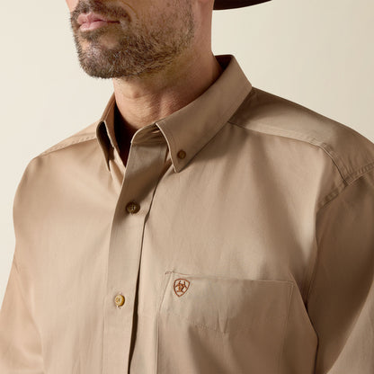 Man wearing a beige Ariat shirt with a brand logo on a neutral background