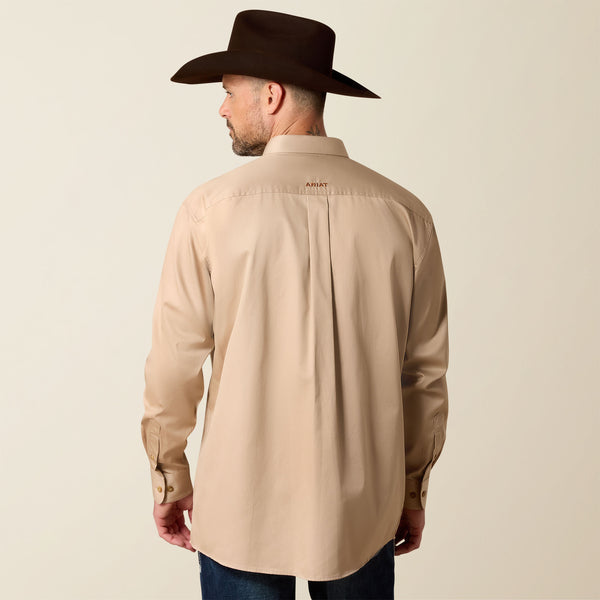 Man wearing a beige Ariat shirt and dark cowboy hat on a beige background