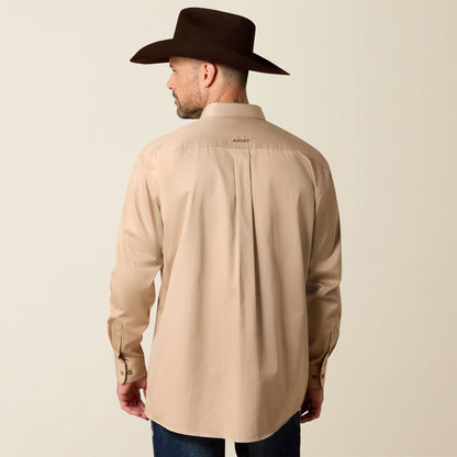 Man wearing a beige Ariat shirt and dark cowboy hat on a beige background