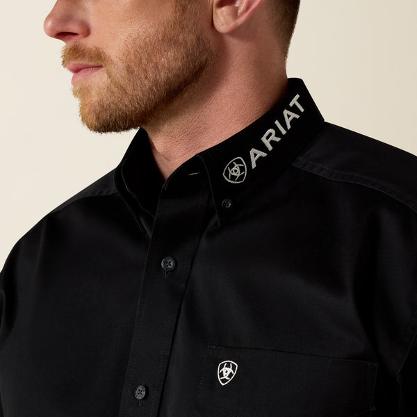 Close-up of a person wearing a black Ariat shirt with the brand logo.