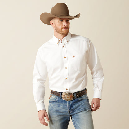Man wearing a white Ariat shirt, brown cowboy hat, and blue jeans on a beige background