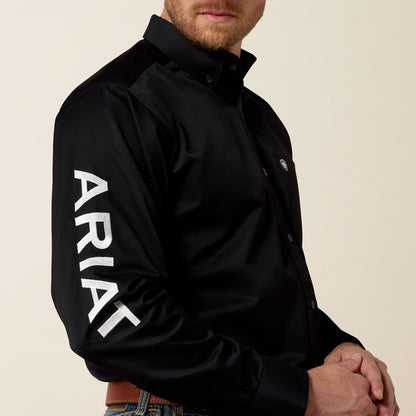Man wearing a black jacket with 'Ariat' branding on a beige background