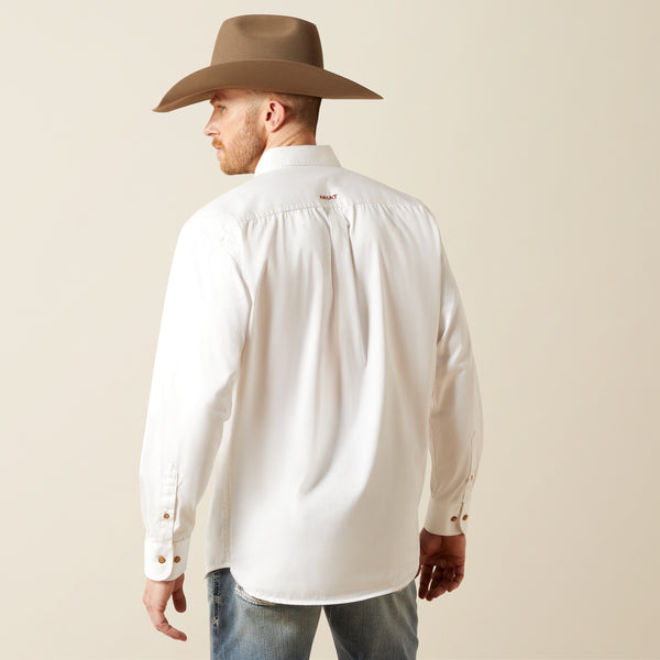 Man wearing a white Ariat shirt and brown cowboy hat against a beige background