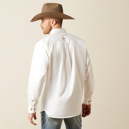 Man wearing a white Ariat shirt and brown cowboy hat against a beige background