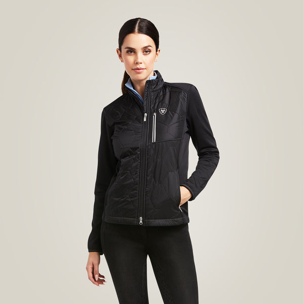 Woman wearing a black jacket with a visible Ariat logo on a light gray background