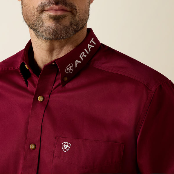 Close-up of a maroon shirt with Ariat logo on a beige background
