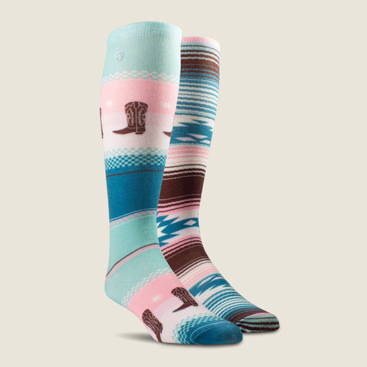 A pair of knee-high Ariat socks with a southwestern pattern, featuring light blue, pink, teal, brown, and white stripes, with cowboy boot motifs and star details, shown against a solid beige background.