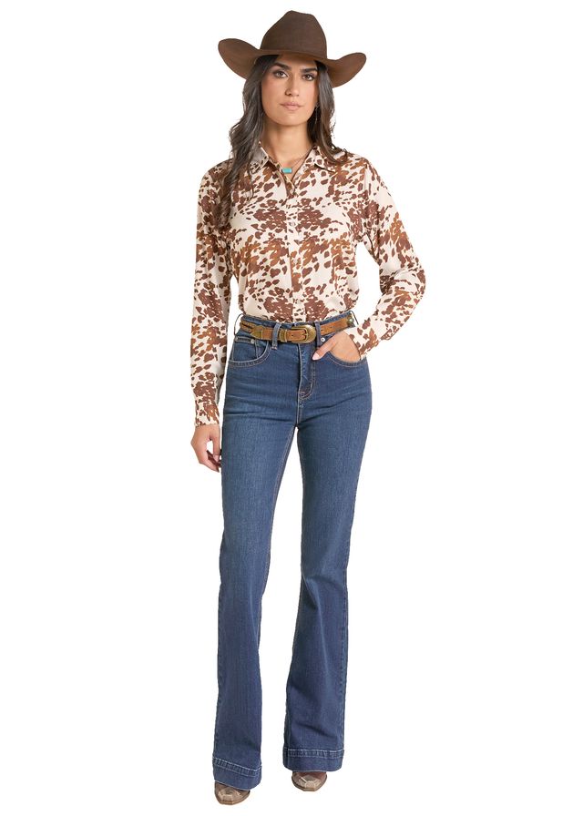 woman wearing a cowhide print shirt from Panhandle Slim and blue jeans and a brown cowboy hat on a white background